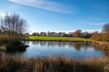 Partly frozen lake with green fields in the Background
