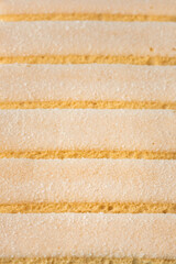 Traditional Italian savoiardi ladyfinger cookies stacked together as a textured background. Macro shot of sweet sponge biscuits for tiramisu cake.