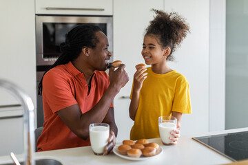 Portrait Of Cute Preteen Black Girl Eating Snacks With Dad In Kitchen