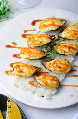 Baked mussels with cheese in shells on rice in a plate