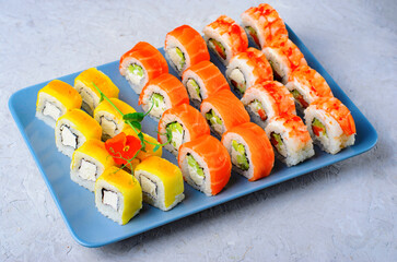 Sushi rolls set with salmon, shrimp and mango on light blue background, Japanese cuisine