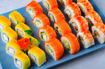 Sushi rolls set with salmon, shrimp and mango on light blue background, Japanese cuisine