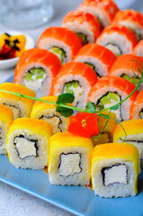 Sushi rolls set with salmon, shrimp and mango on light blue background, Japanese cuisine