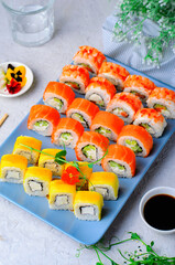 Sushi rolls set with salmon, shrimp and mango on light blue background, Japanese cuisine