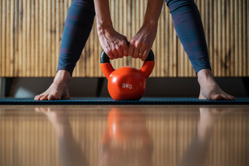 Naklejka premium Closeup view of a woman working out at home with kettlebell weight