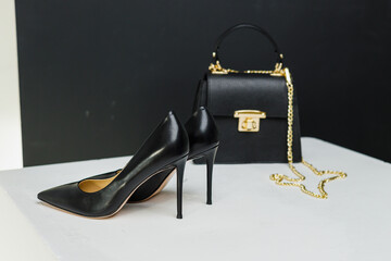 Elegant women's pumps with heels stand next to a black handbag on a white background. Place for...
