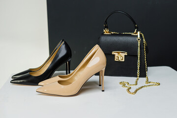 Elegant women's pumps with heels stand next to a black handbag on a white background. Place for...