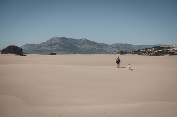 A male photographer with a backpack walks along Patara beach. Panorama of sand dunes.