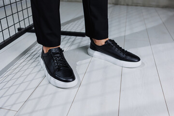 Modern men's shoes. Male legs in black pants and black casual sneakers. Men's fashionable shoes