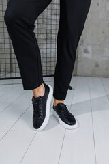 Modern men's shoes. Male legs in black pants and black casual sneakers. Men's fashionable shoes