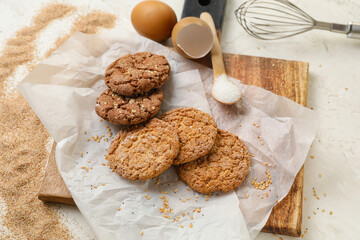 Wooden board with delicious cookies on light background, closeup