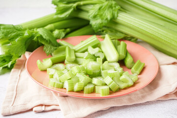 Plate of cut fresh celery on light background, closeup