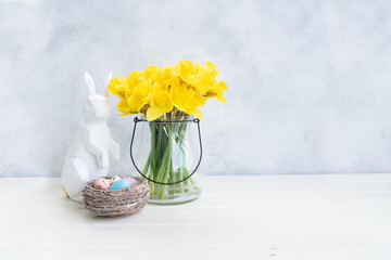 Easter Egg hunt with Easter white bunny and daffodils in vase