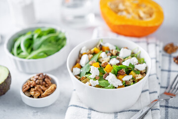 Roasted pumpkin avocado arugula goat cheese salad in a plate