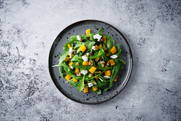 Roasted pumpkin avocado arugula goat cheese salad in a plate