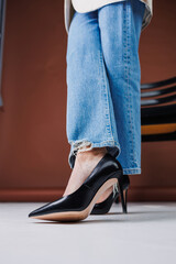 Beautiful female legs in jeans and black leather stilettos. Women's winter shoes