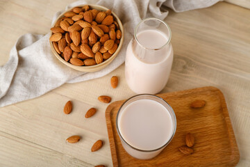 Board with glass, bottle of almond milk and nuts on wooden background