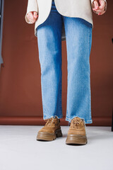 Close-up of female legs in jeans and brown casual suede sneakers. Women's summer shoes