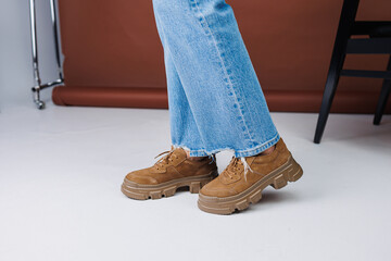 Close-up of female legs in jeans and brown casual suede sneakers. Women's summer shoes