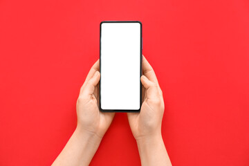 Female hands with modern mobile phone on red background