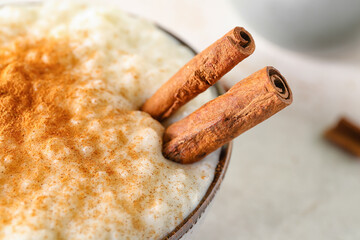 Bowl with delicious rice pudding and cinnamon on white table, closeup
