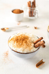Bowl with delicious rice pudding and cinnamon on white table