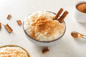 Bowl with delicious rice pudding and cinnamon on white table