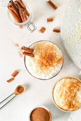 Composition with bowls of delicious rice pudding and cinnamon on white table