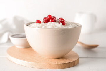 Bowl with delicious rice pudding and cranberry on white wooden table