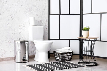 Interior of restroom with toilet bowl, table and folding screen