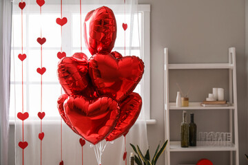 Heart-shaped balloons near window in bedroom decorated for Valentine's Day