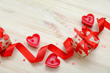 Gifts with ribbon, candles and hearts on light wooden background. Valentine's Day celebration
