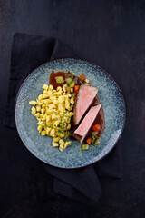 Tafelspitz Braten vom Kalb mit schwäbischen Spätzle and Gemüse serviert mit Dunkelbier Sauce als Draufsicht auf einem Nordic Design Teller 