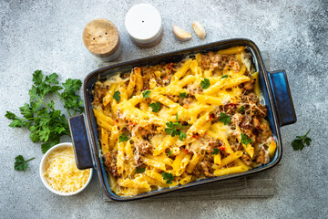 Pasta penne with minced meat, cheese and creamy sauce in frying pan. Mac and cheese. Top view on...