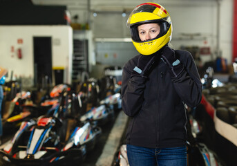 Portrait of girl in helmet posing near a kart at track