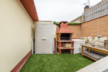 Terrace of a single-family home with artificial grass, resin cabinet and built-in barbecue grill