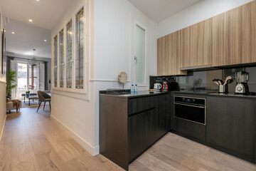 Long corridor that leads to a house with marble floors and stoneware walls with access to internal wooden stairs next to a walkway that leads to a living room with white wooden balconies.