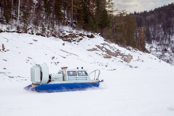 A hovercraft glides over the surface of a frozen river. Winter tourism.