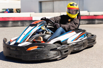 Glad cheerful positive smiling woman driving sport car for karting in a circuit lap outdoor in...