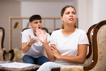 Portrait of frustrated woman in living room, while disgruntled husband scolds her
