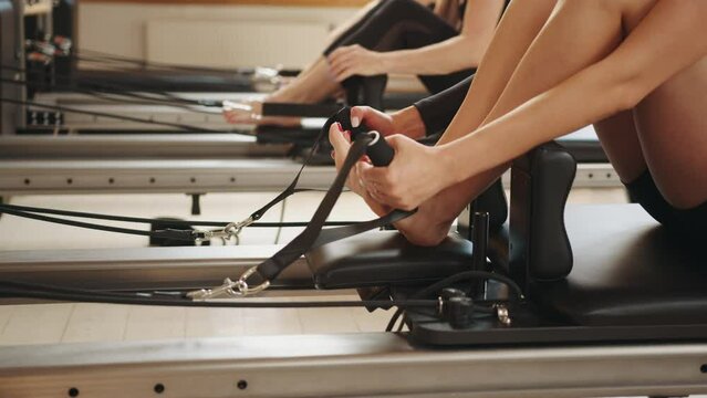 Rehabilitation and healthy lifestyle, myofascial release concept. Group of active sportive woman practicing pilates in a row on reformers bed in fitness studio
