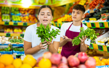 Supermarket salesman helps girl to choose fresh mint