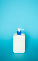 White square bottle with a blue dispenser for liquid soap, shampoo, gel on blue background.