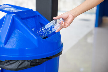 Close up female throwing empty bottle to trash, woman hand throwing empty plastic water bottle into...