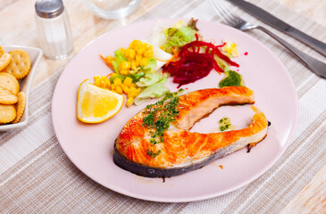 Just cooked salmon steak with beetroot, corn, lettuce salad on plate.