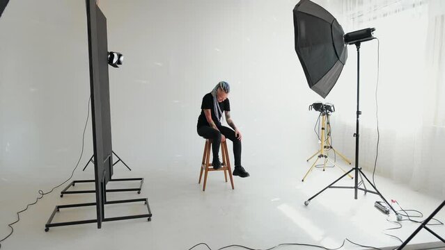 a model girl with dreadlocks and a tattoo is sitting in a white studio against the background of studio light. Gay girl. Concept of gender expression, identity and diversity. gender person. Feminism
