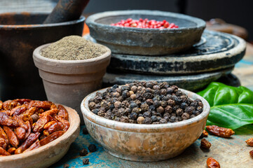 Indian spices collection, dried black peppercorns and another spices in clay bowls