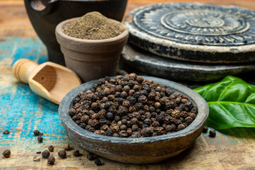Indian spices collection, dried black peppercorns and another spices in clay bowls