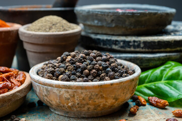 Indian spices collection, dried black peppercorns and another spices in clay bowls