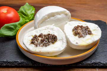 White balls of Italian soft cheese Mozzarella di Bufala Campana stuffed with black truffles mushrooms